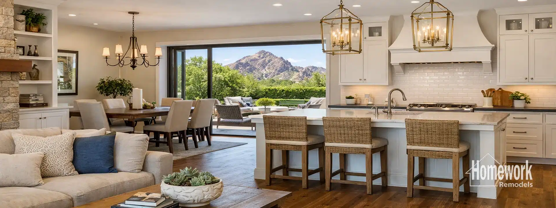 Spacious open-concept kitchen and dining area, perfect for kitchen remodeling inspiration in Arcadia, with white cabinets, large island with wicker stools, wooden dining table, cozy living area, and mountain view through sliding glass doors.