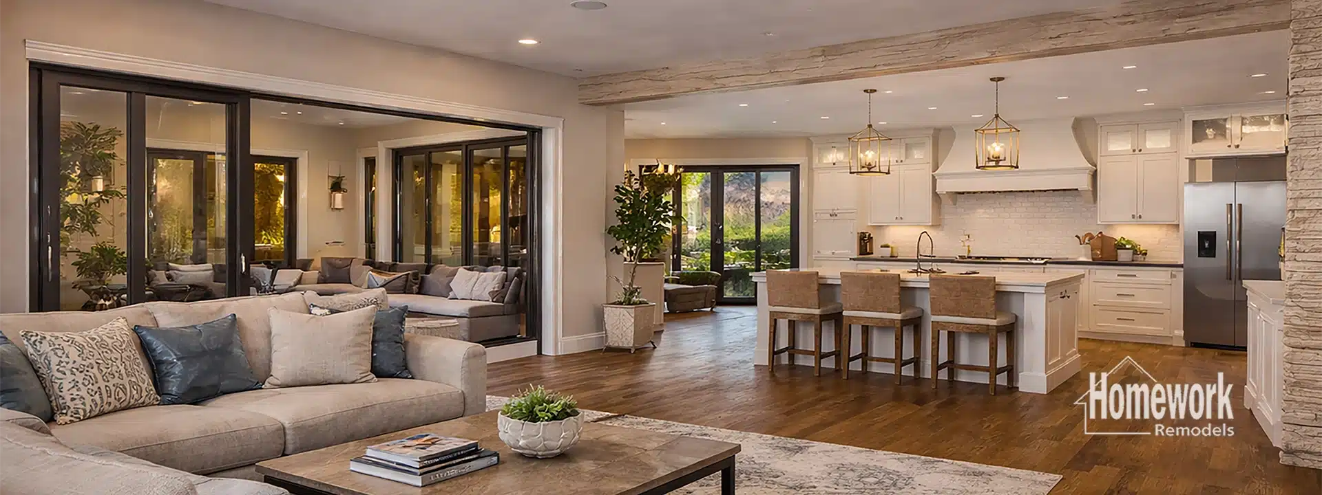 Spacious open-concept living room and kitchen in Arcadia Phoenix with neutral tones, modern furniture, large windows, wood floors, and a central island—created by removing load-bearing walls. Homework Remodels logo is visible in the corner.