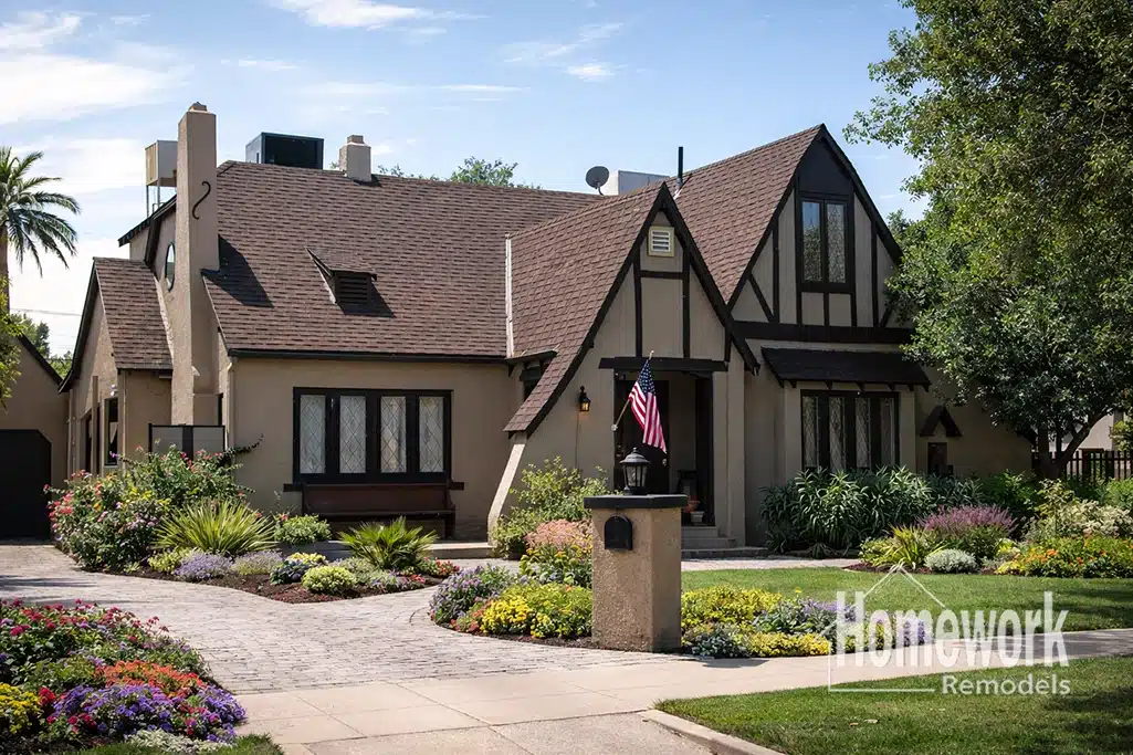 A charming Tudor-style house in Willo with steep gable roofs, decorative timber framing, and lush landscaping. The “Homework Remodels” logo hints at expert whole-home remodeling while colorful flowers border the curved stone walkway.
