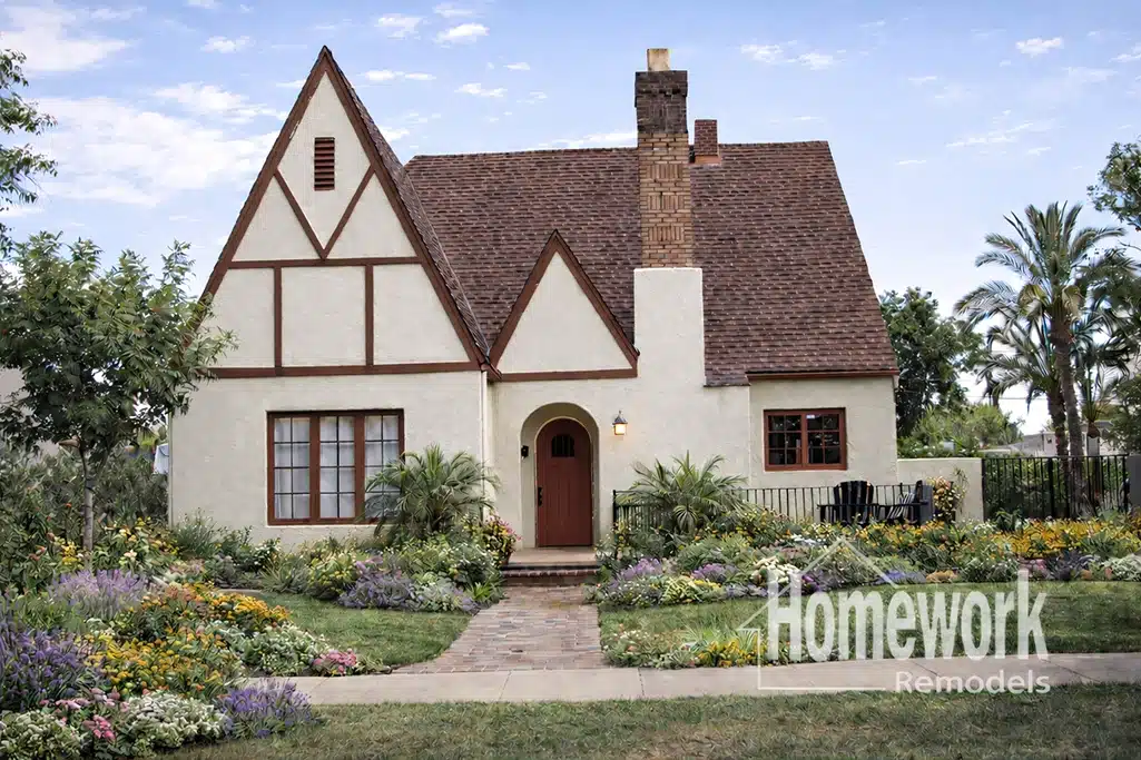 F.Q. Story Historic District: A charming Tudor-style house with a steep roof, brick chimney, and lush landscaped garden, featuring colorful flowers and greenery. The logo Homework Remodels is visible in the bottom right corner.