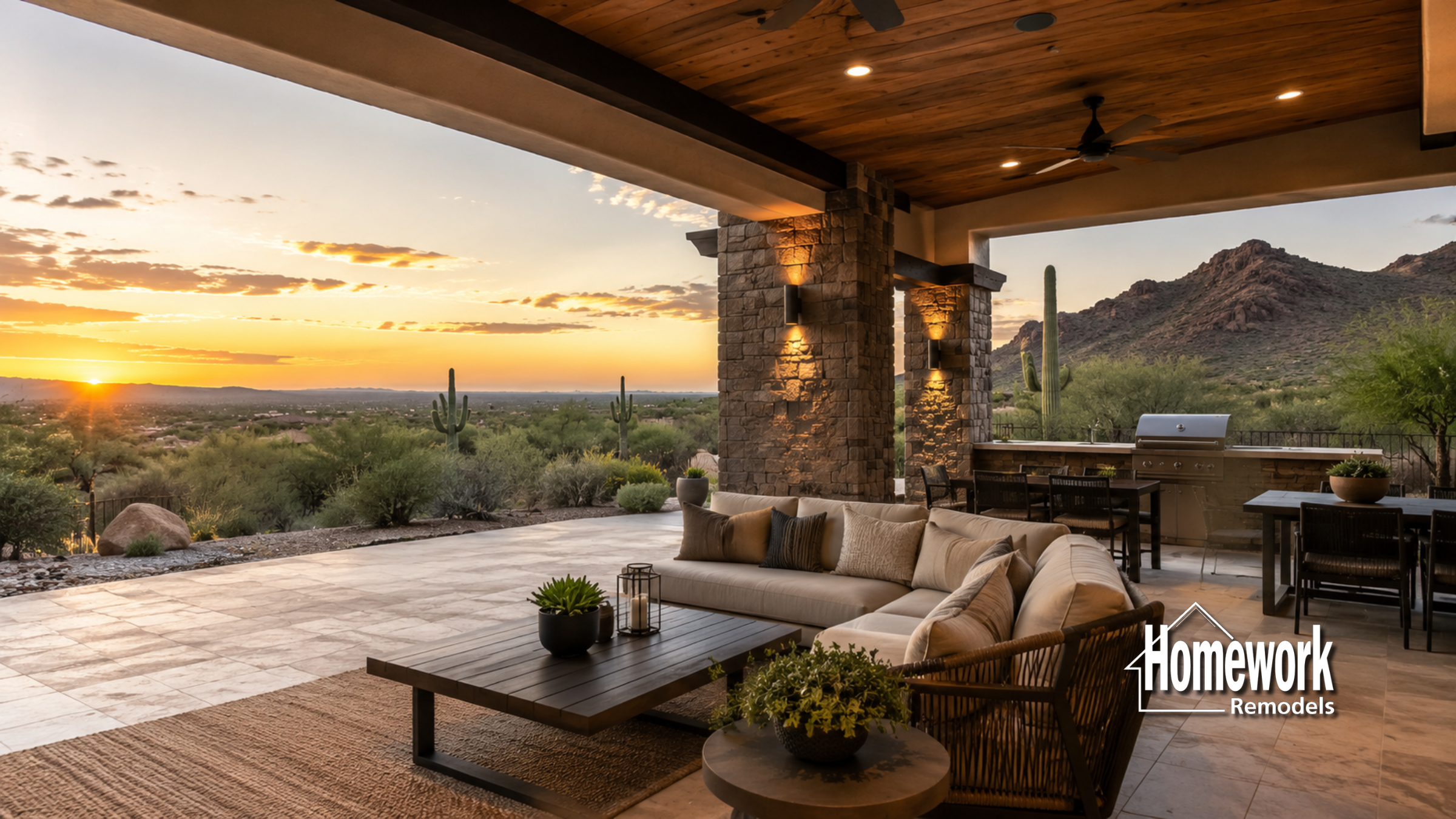 A luxurious covered patio and ramada with a sectional sofa and coffee table overlooks a Cave Creek desert landscape at sunset, featuring mountains, cacti, and an outdoor dining area with a grill. Homework Remodels logo is in the corner.