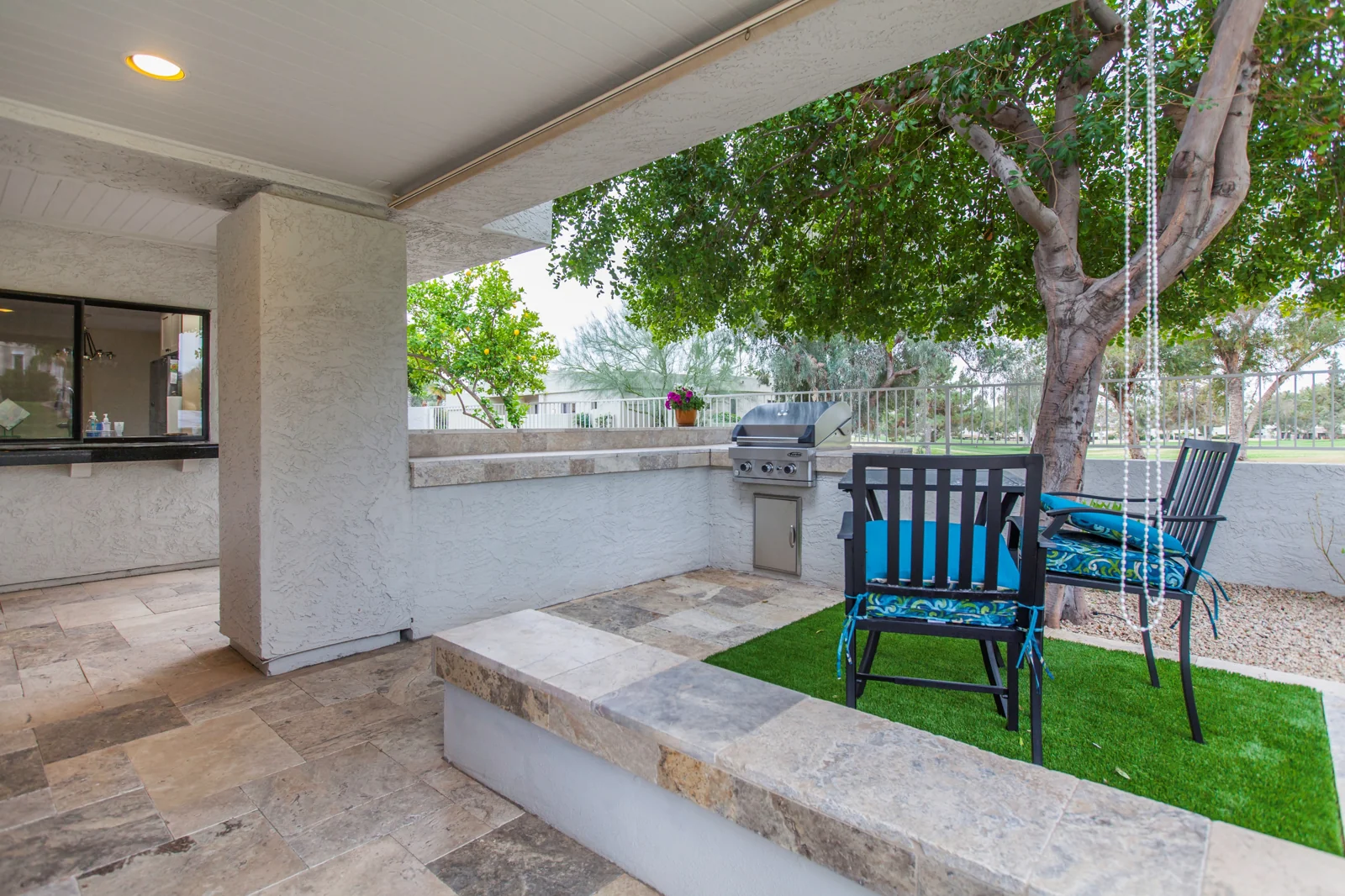Outdoor barbecue and serving peninsula beside new travertine paving and a small lawn seating area