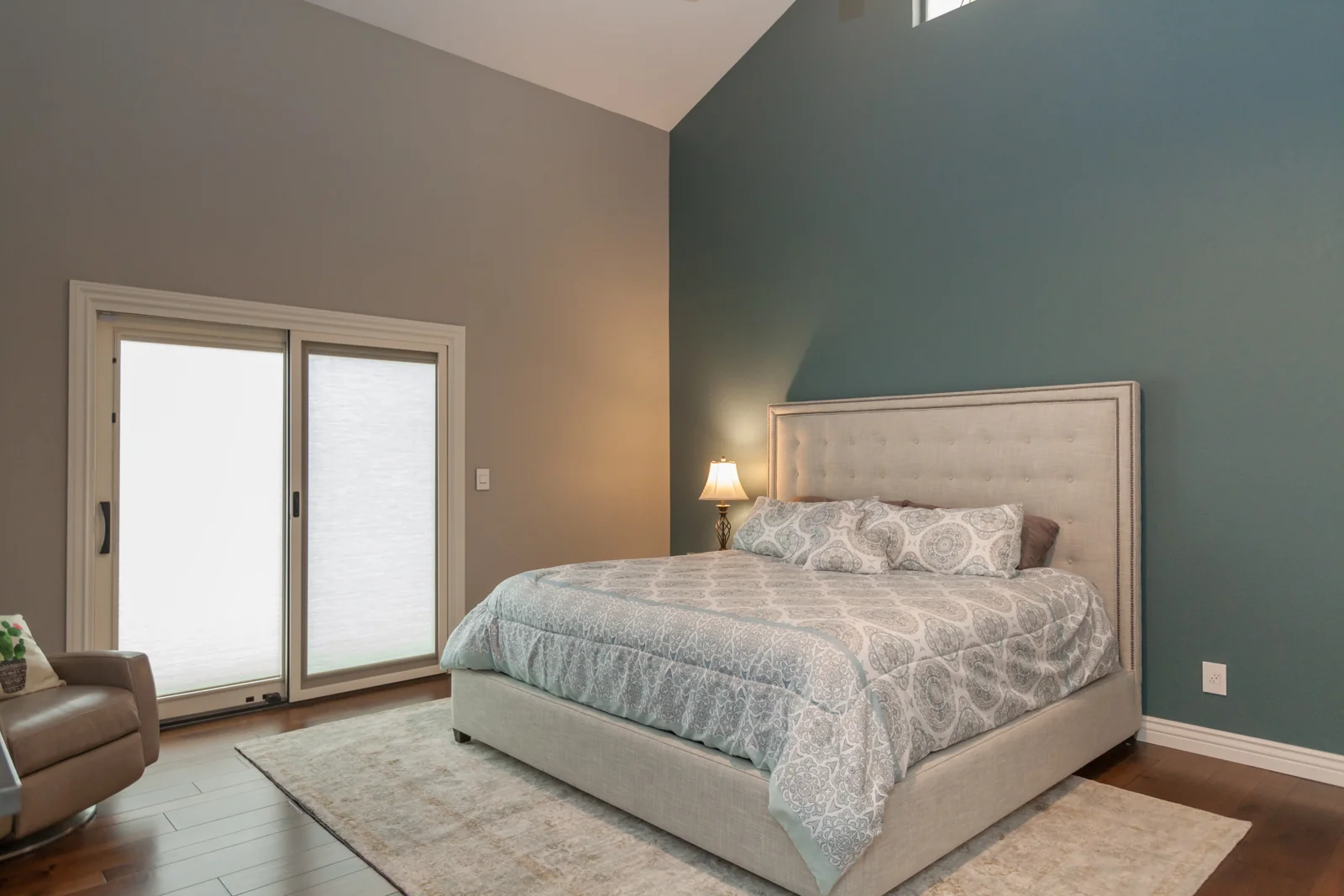 Updated primary bedroom with a blue accent wall, white millwork, and a sliding glass patio door