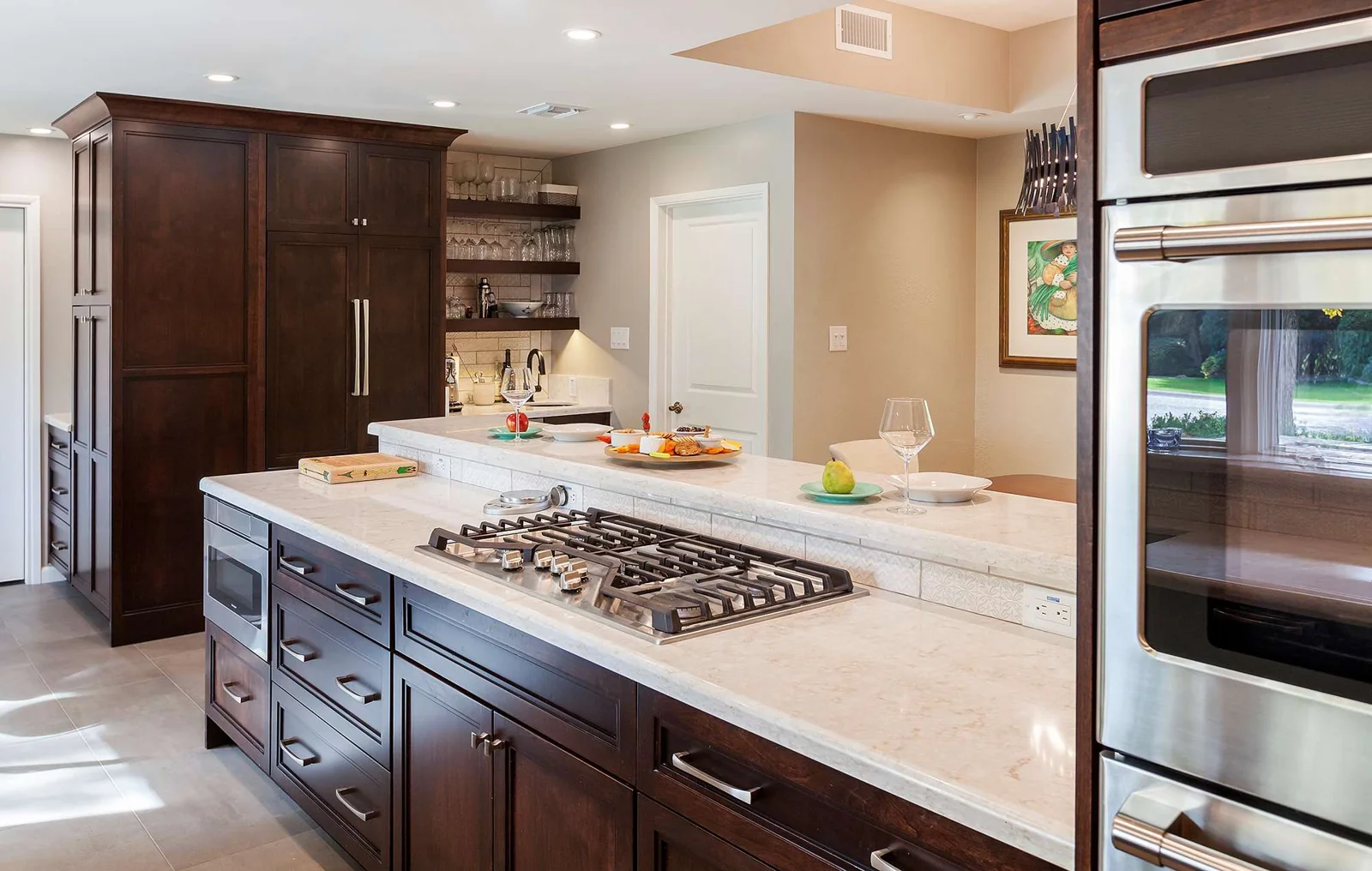 Central Phoenix open concept kitchen remodel with dark custom cabinetry, a gas cooking peninsula, double ovens, and a ceiling-flush hood