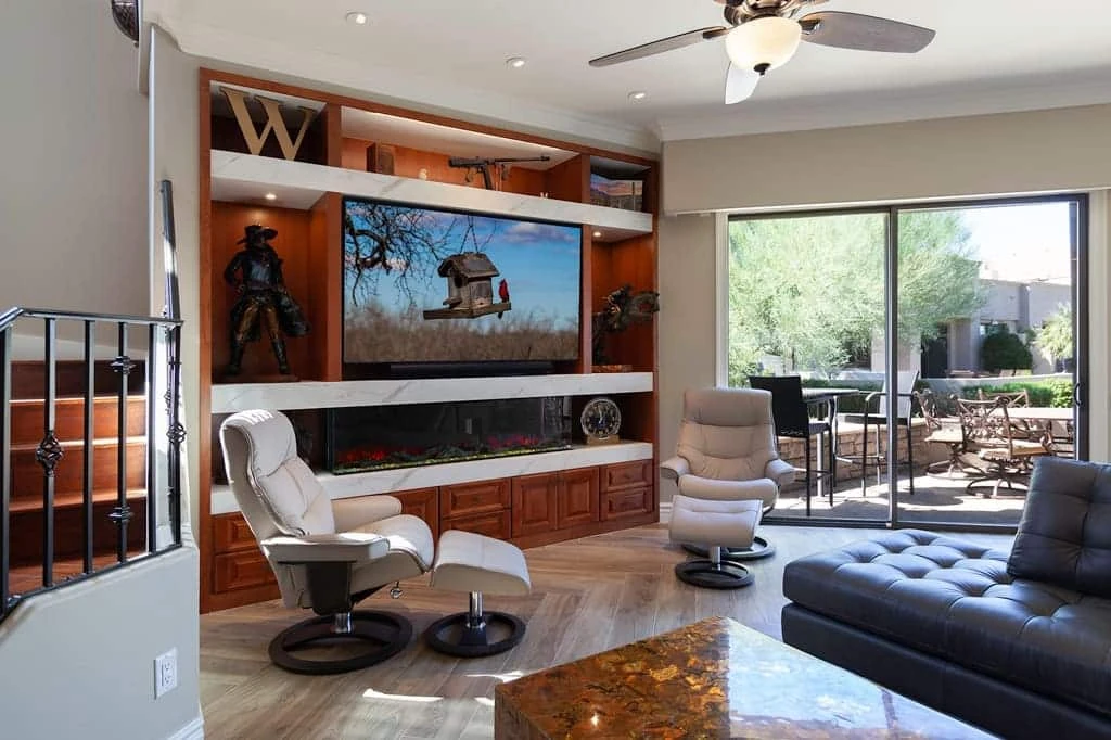 Scottsdale fireplace remodel with custom wood cabinetry, porcelain shelves, bronze sculptures, and an electric fireplace in a bright Gainey Ranch living room