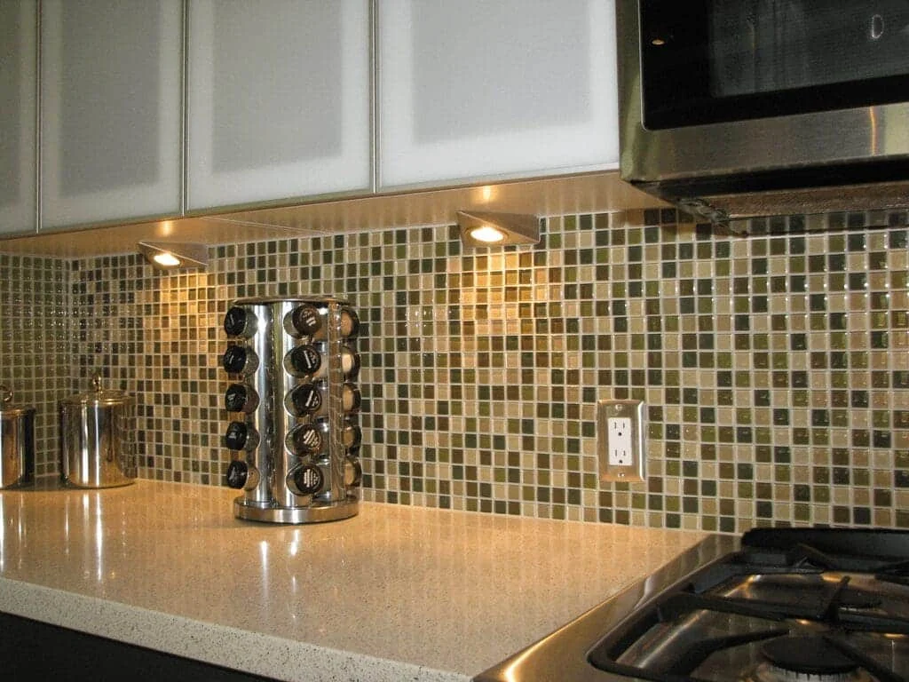 Glass mosaic kitchen backsplash illuminated by undercabinet lights