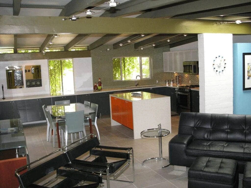 Kitchen, dining area, and living room connected beneath exposed beams in a Ralph Haver home