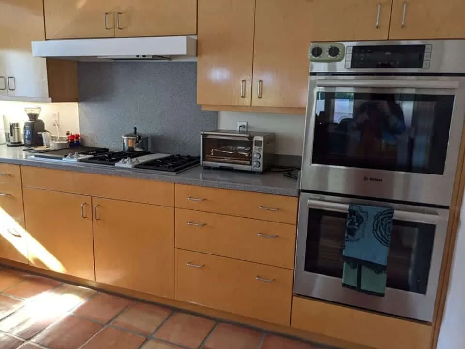 Original cooking wall with a propane cooktop, wood cabinetry, and older built-in ovens