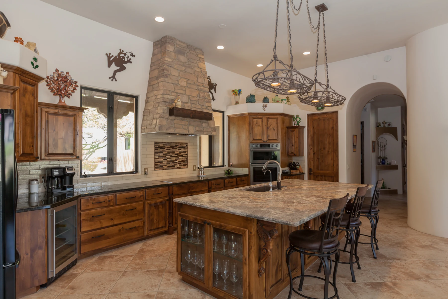 Completed kitchen with a stone veneer hood and brown pine mantel centered between two windows