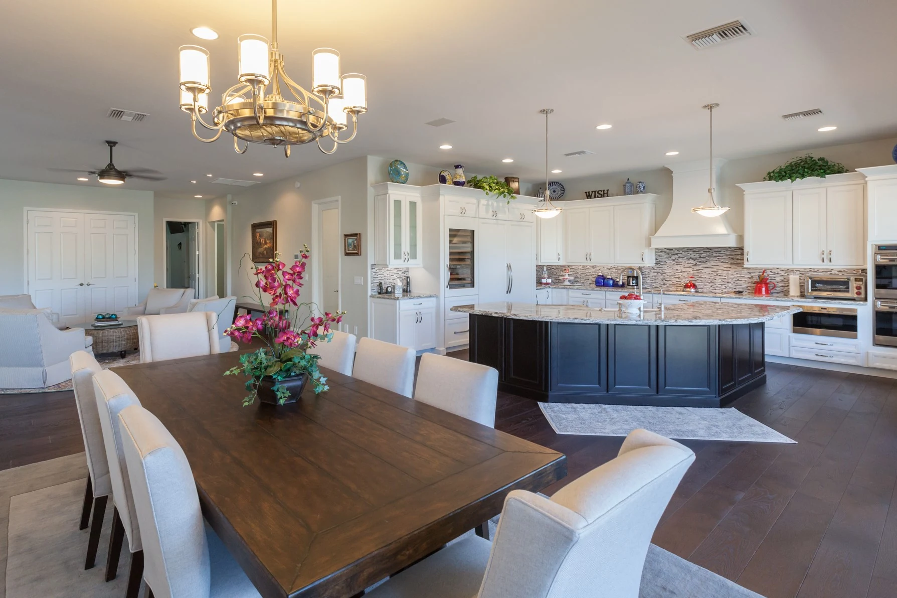 Completed Chandler kitchen with a dark island, white cabinets, granite counters, and adjoining dining and seating areas