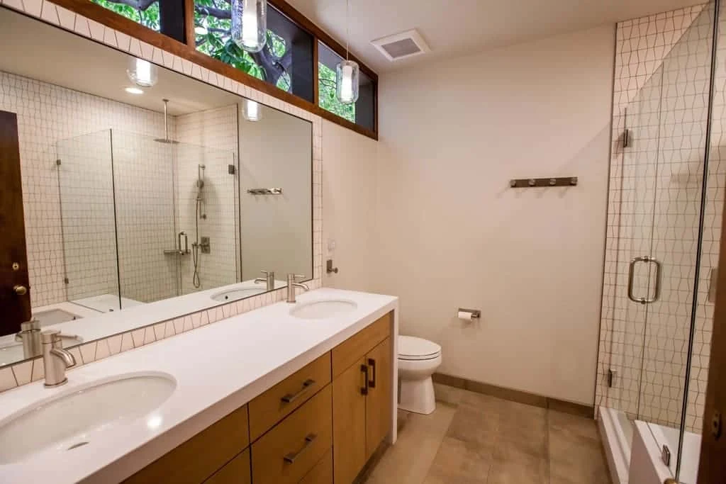 Finished Phoenix bathroom with a double-sink wood vanity, white countertop, wide mirror, and stained-glass windows