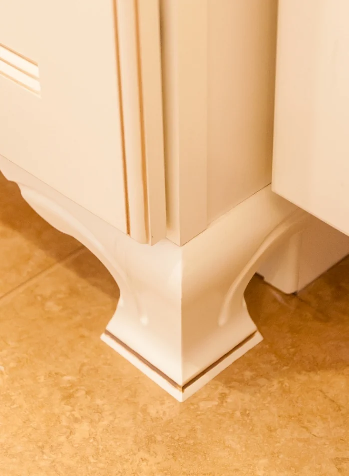 Decorative cabinet foot and glazed panel detailing at the base of a finished bathroom vanity
