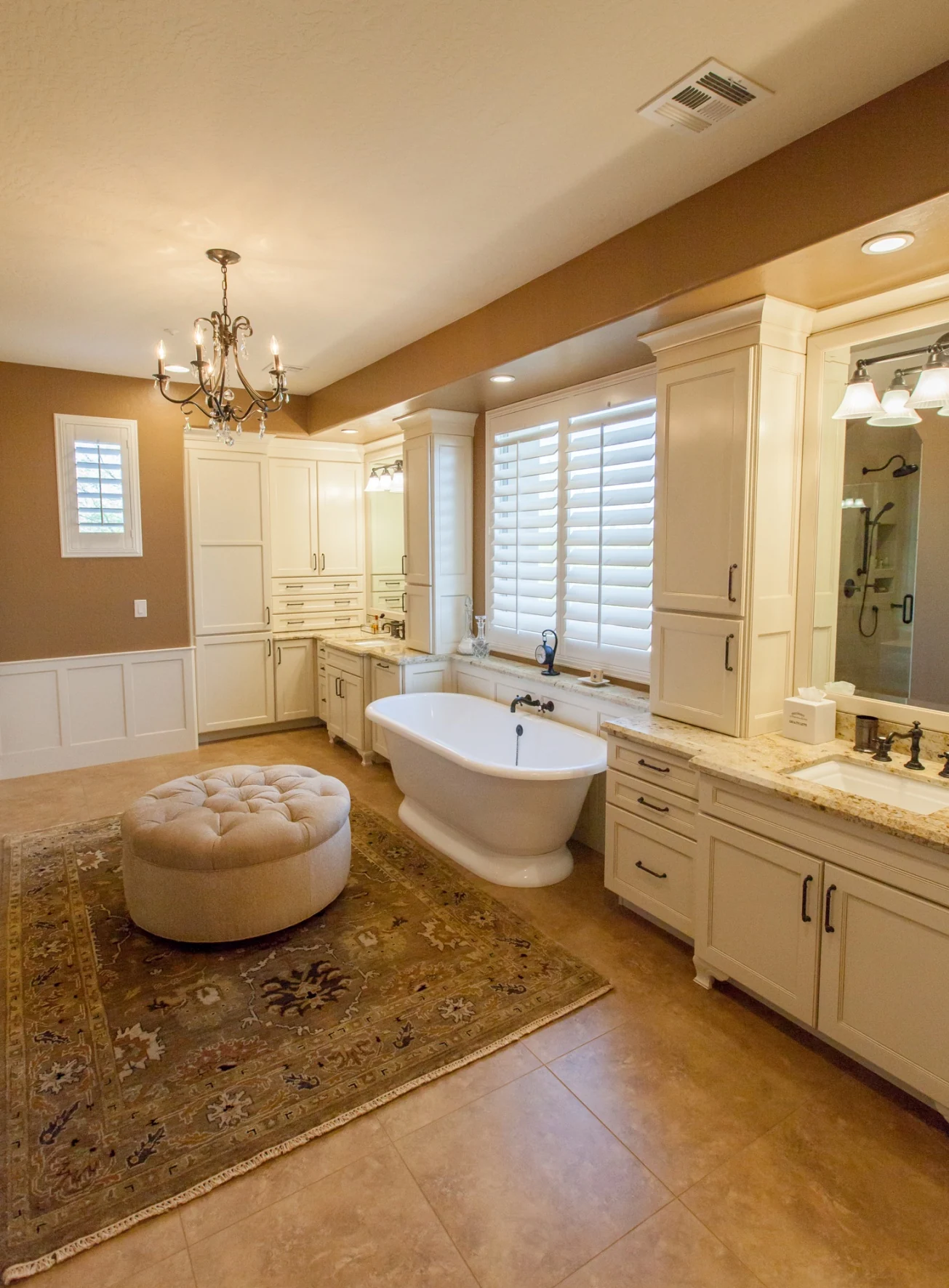 Completed bathroom with freestanding tub, paneled walls, glazed cabinetry, and organized vanity storage