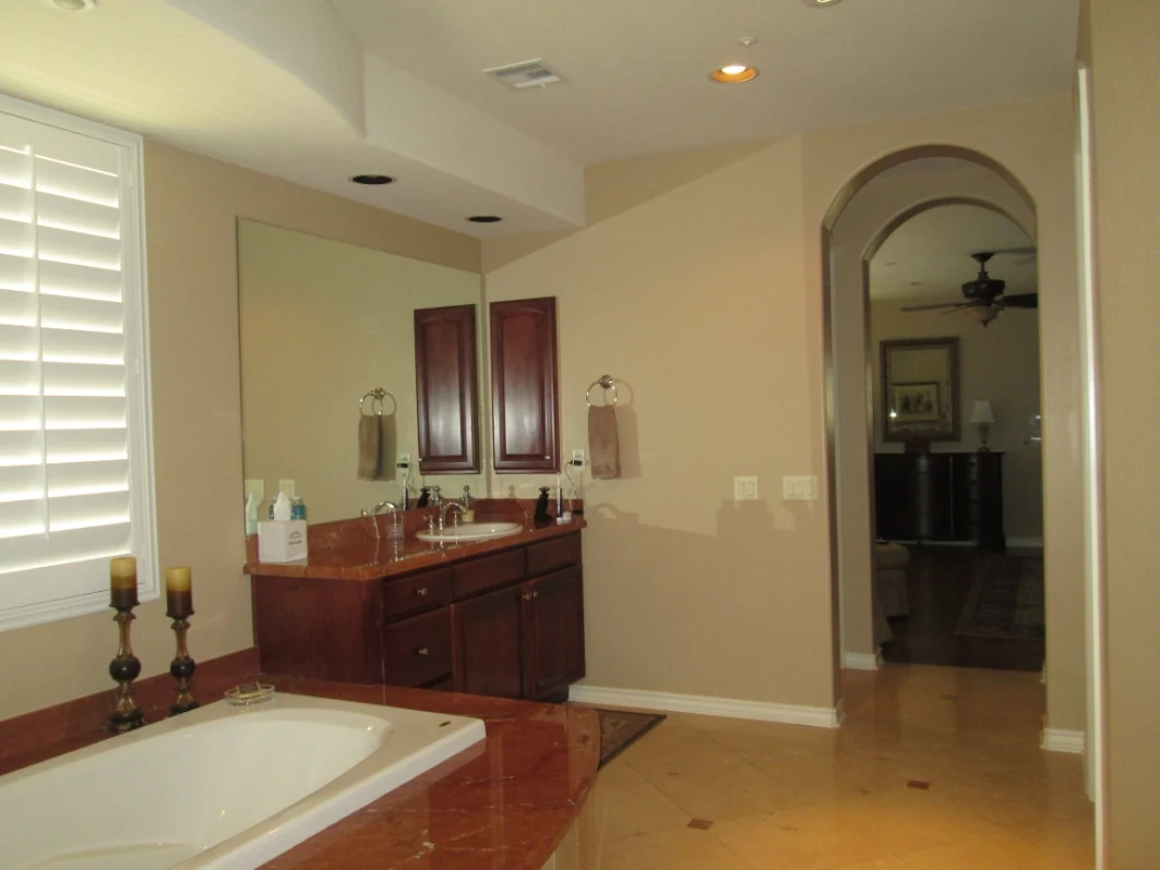 Original bathroom vanity, wood cabinets, wall mirrors, and the large tub deck before remodeling