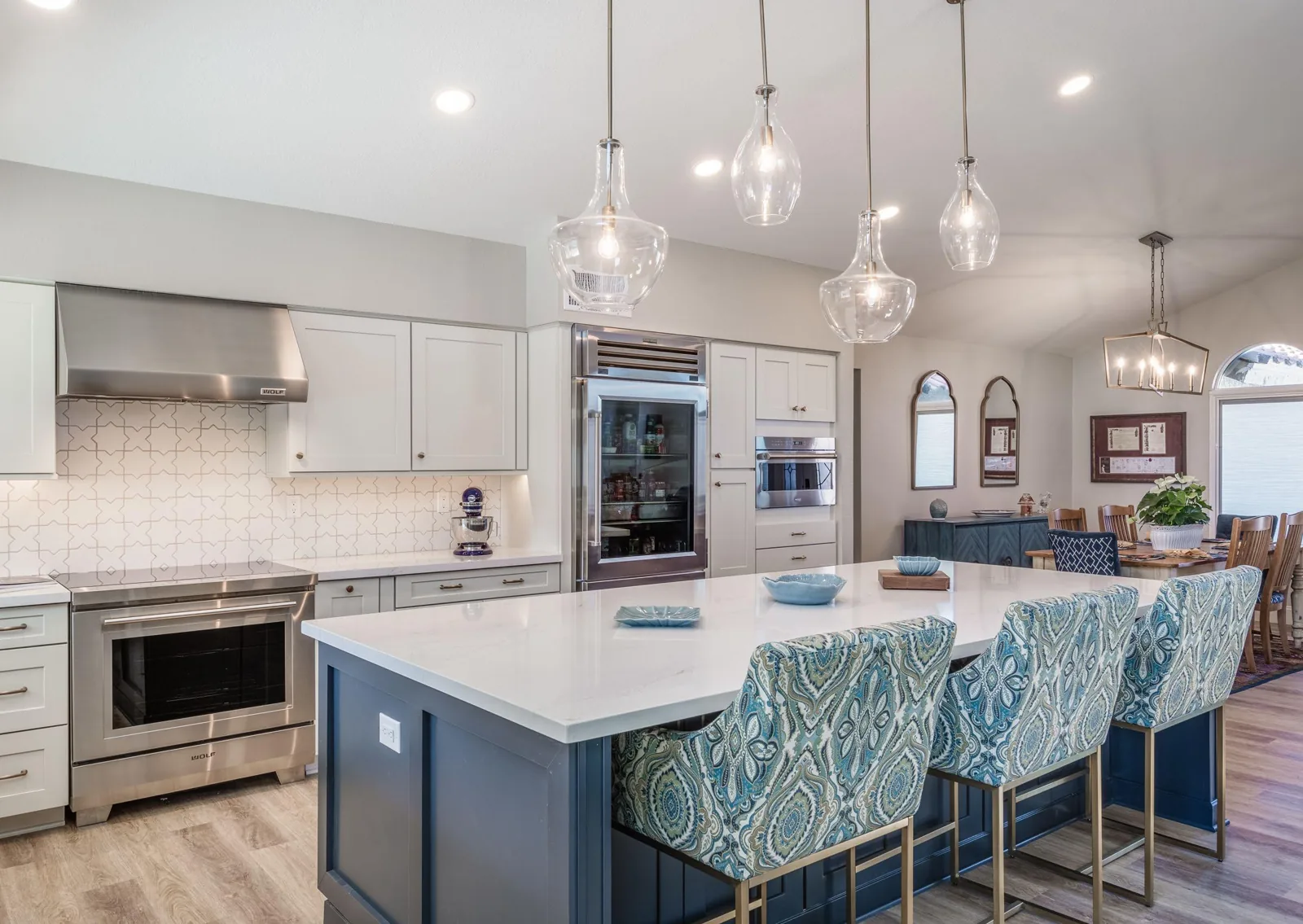 Tempe whole-home remodel with an open kitchen, navy island, patterned upholstered stools, white cabinetry, and pendant lighting