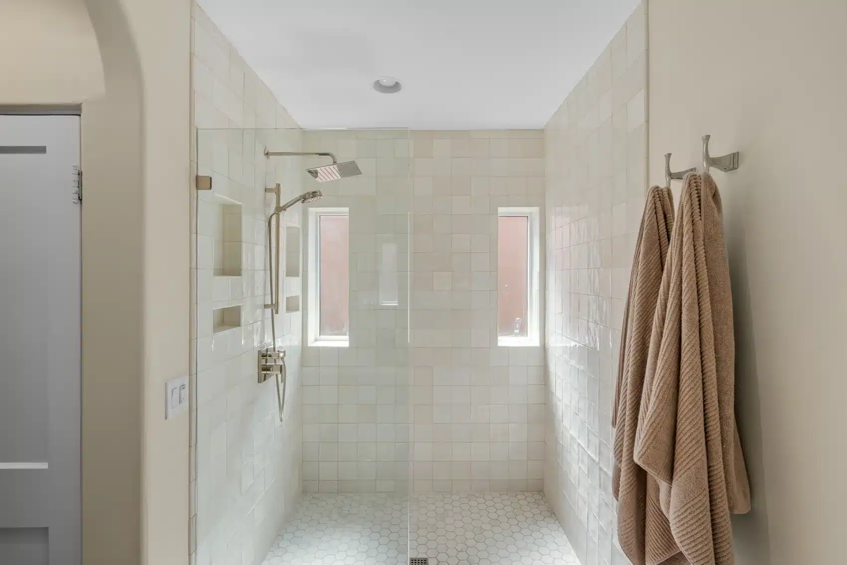 Finished curbless shower with ivory tile, dual niches, privacy windows, and glass enclosure in a historic Willo bathroom