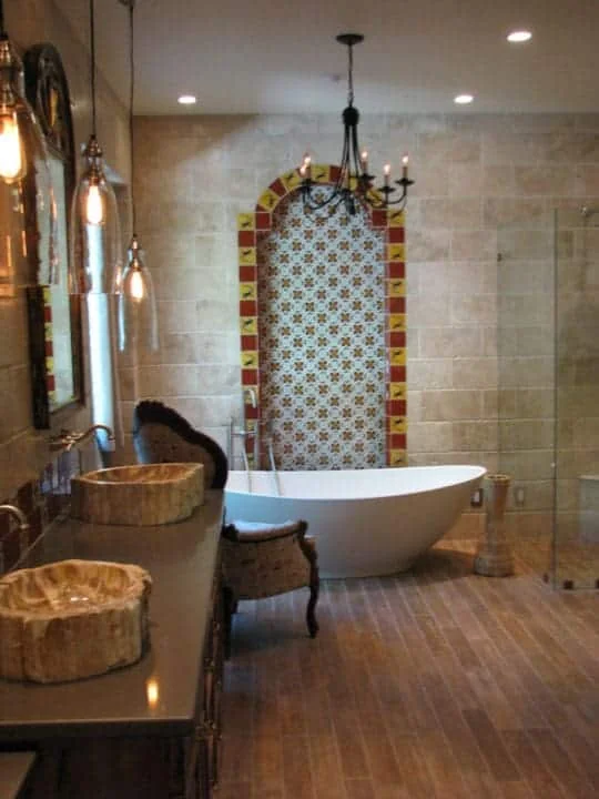 Two petrified wood vessel sinks on a dark bathroom vanity with pendant lighting, mirrors, and the tub beyond