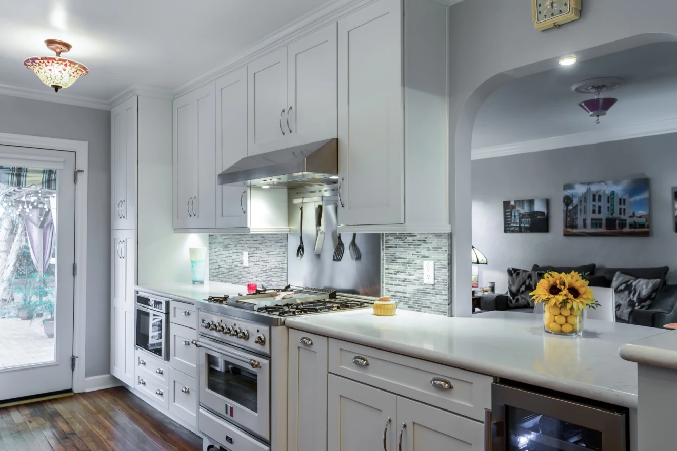 Completed Willo kitchen with linen Shaker cabinets, white quartz counters, a gas range, and an arched pass-through to the living room