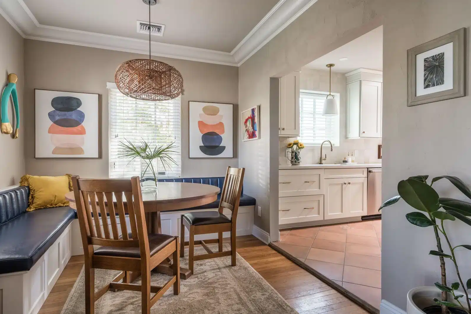 Dining area after kitchen remodeling with a widened opening, wood table, and upholstered bench
