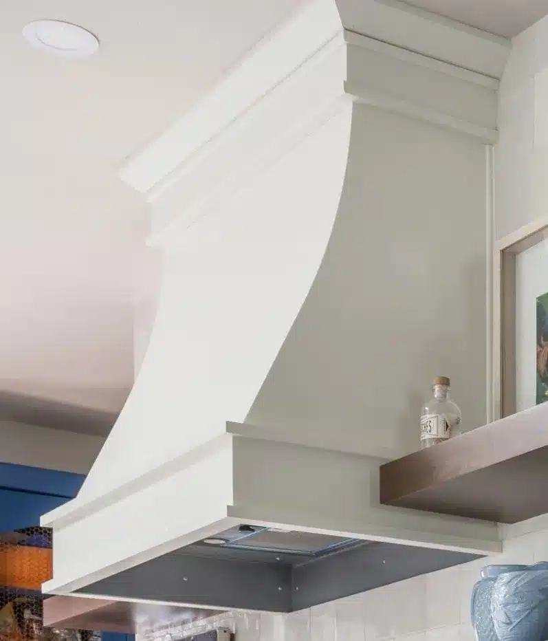 Multi-piece crown molding wrapping the top of the cream kitchen range hood