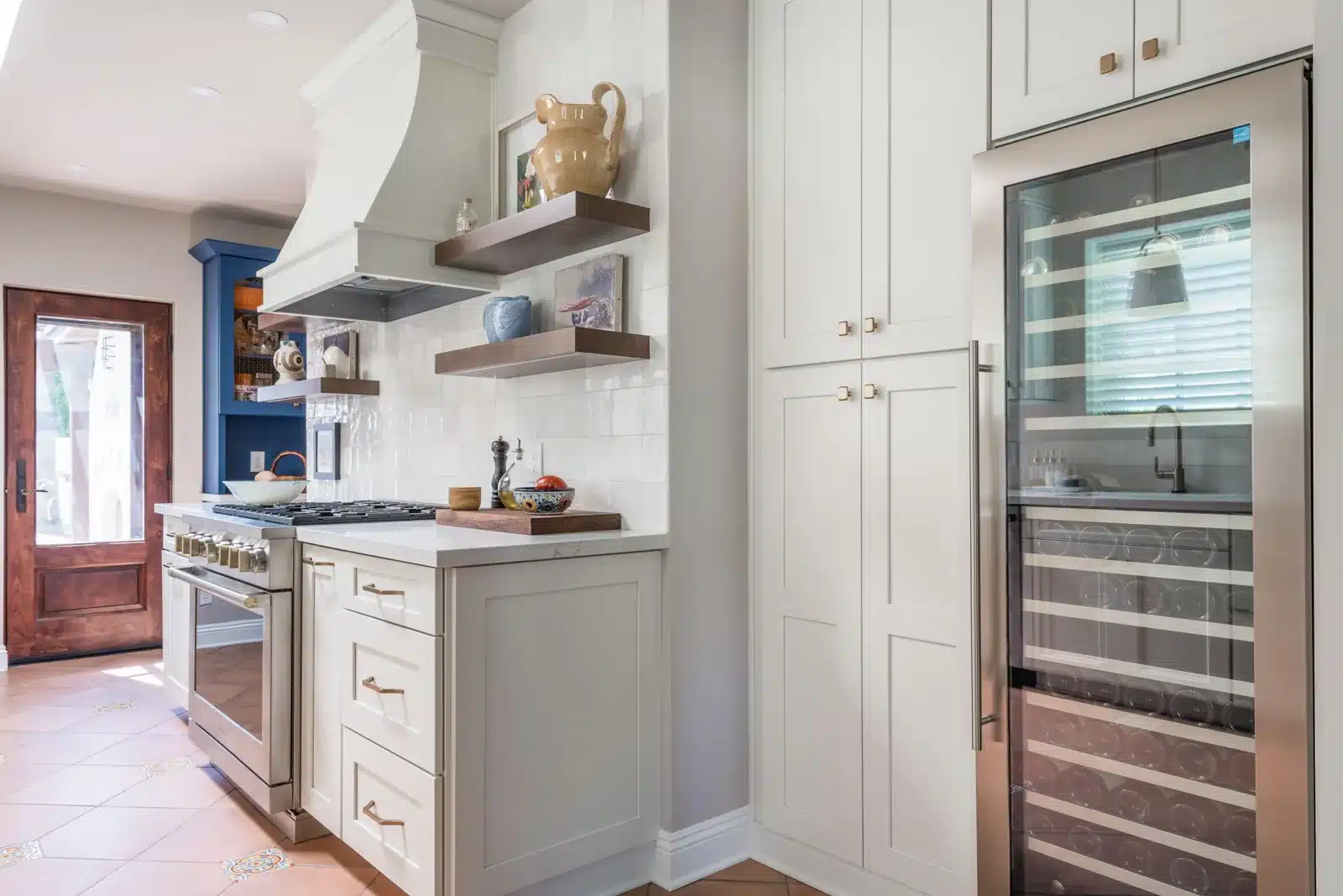 Spanish Colonial kitchen remodel in Phoenix with cream cabinets, a custom range hood, floating wood shelves, and a wine refrigerator