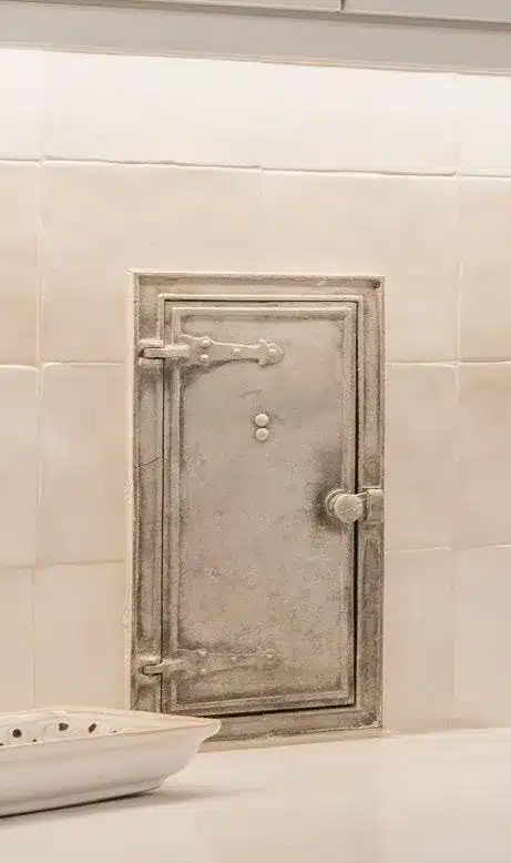 Original metal milk door restored within the kitchen tile backsplash