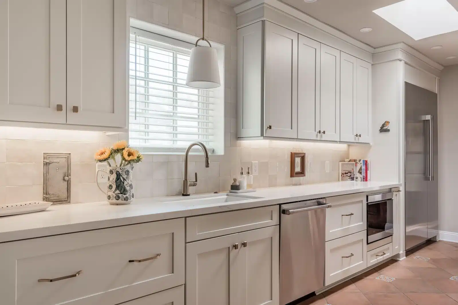 Historic kitchen after remodeling with a large sink, raised wall cabinets, tiled window opening, and column refrigeration